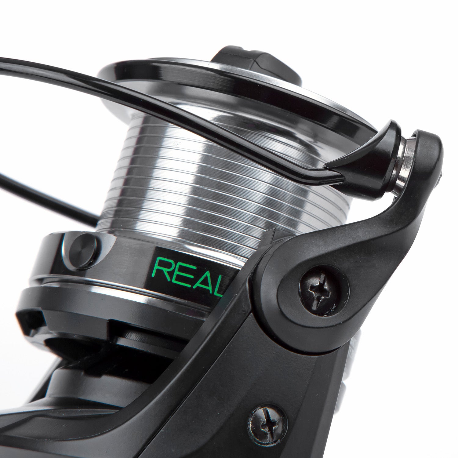 Close-up of a fishing reel with 'REAL' branding on a white background